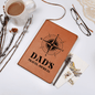 Brown leather journal travel for dad with compass design, pen, eyeglasses, and coffee cup on white background