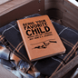 Leather journal with funny journal prompts text and fist bump graphic on plaid clothes inside a suitcase