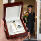 Graduation Cap Name Necklace by Someone Said Gift displayed in wooden box with graduate in cap and gown in background
