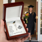 Graduation Cap Name Necklace by Someone Said Gift displayed in wooden box with graduation card and graduate in background