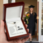 Graduation Cap Name Necklace displayed in a wooden box with a congratulatory card and graduate in background