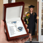 Graduation Cap Necklace with the name displayed in wooden gift box with graduate holding flowers in background