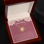 Gold personalized love knot necklace with crystal center displayed in wooden gift box on Dear Mom card